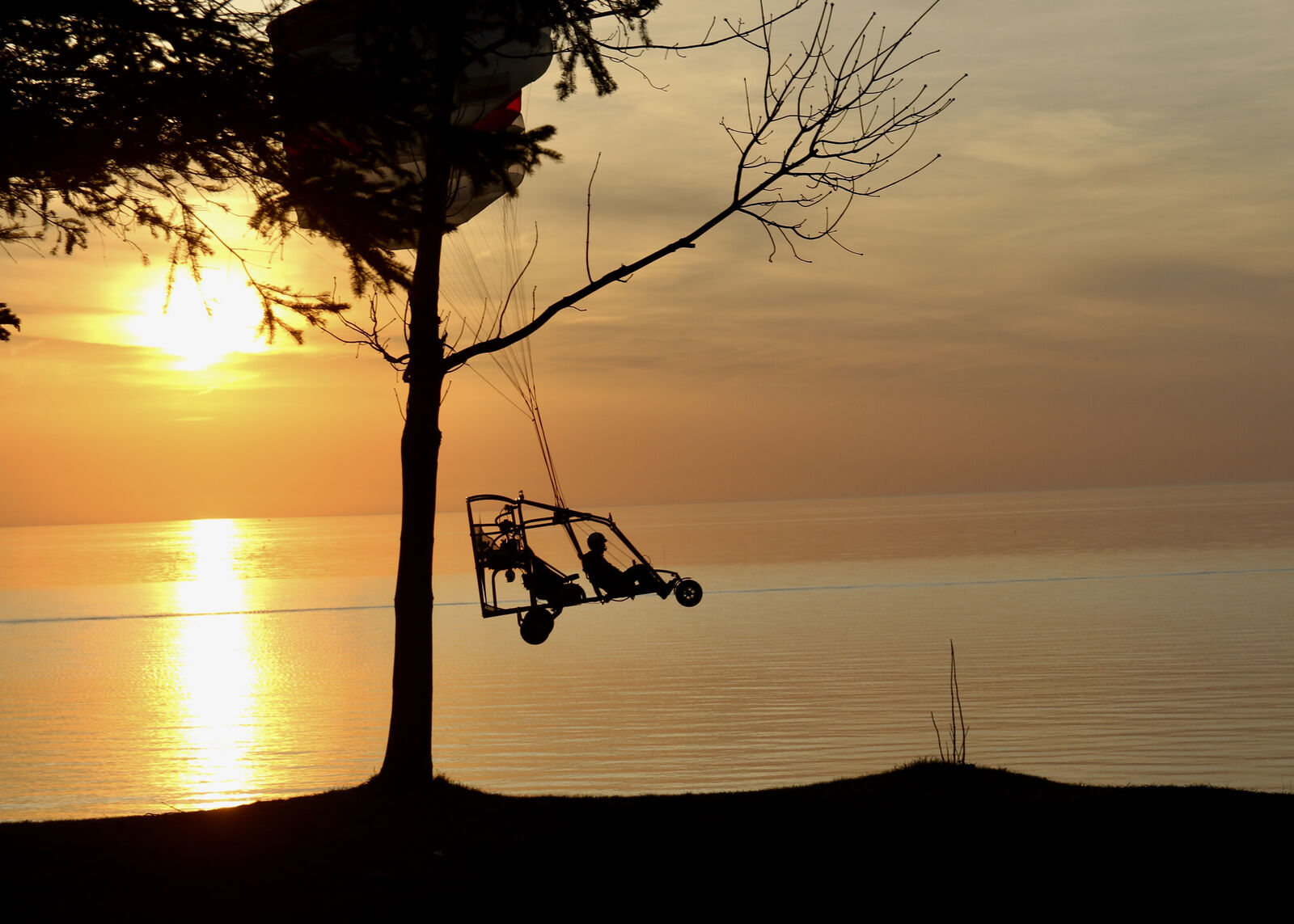 Powered paraglider silhouetted against a golden Lake Erie sunset in Brant